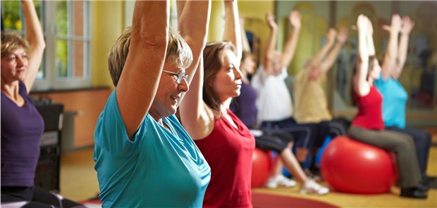 Personen beim Lungensport mit erhobenen Armen auf Gymnastikbällen.