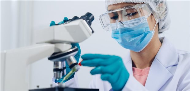 Eine Wissenschaftlerin untersucht eine Proben im Labor unter einem Mikroskop.