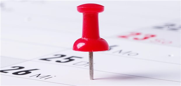 In einem Kalender ist ein Woochentag mit einer roten Nadel markiert.