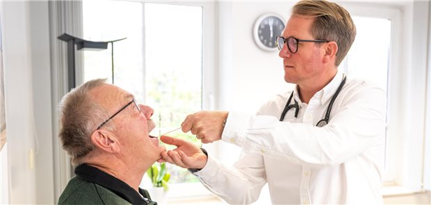 Blick in den Rachen des Patienten: Ein Hausarzt diagnostiziert eine Atemwegserkrankung.