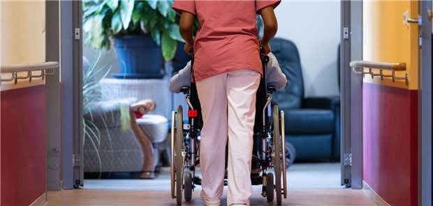 Eine Pflegekraft schiebt einen Menschen im Rollstuhl