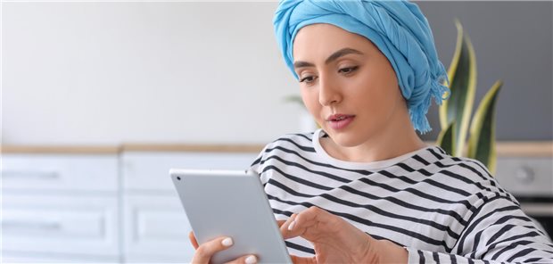 Eine Frau mit Tuch um den Kopf am Tablet