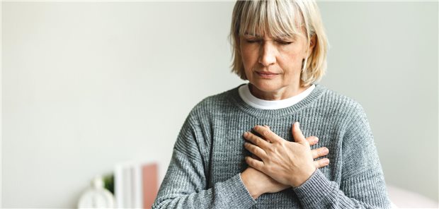 Eine Frau fässt sich mit den Händen an die Brust