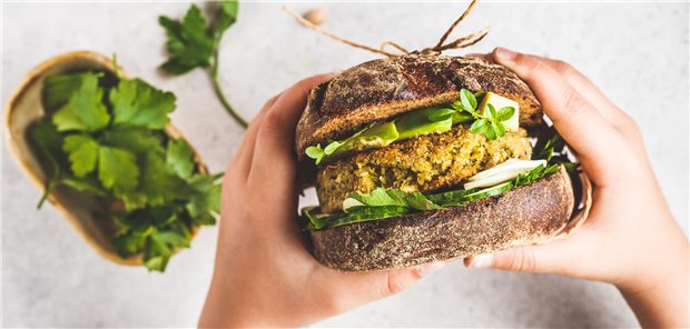 Eine Person hält einen veganen Burger in den Händen.