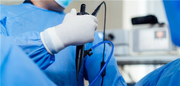 Ein Arzt in blauer OP-Kleidung führt eine Endoskopie in steriler Umgebung durch.