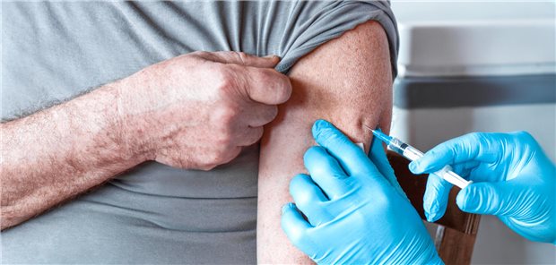 Ein Mann bekommt eine Injektion in den linken Oberarm.