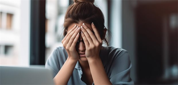 eine Frau hält den Kopf aufgestützt und die Hände vor den Augen