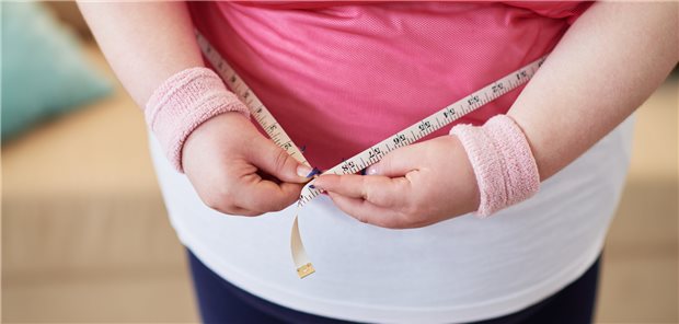 Close-up of overweight woman measuring her waist with tape measure