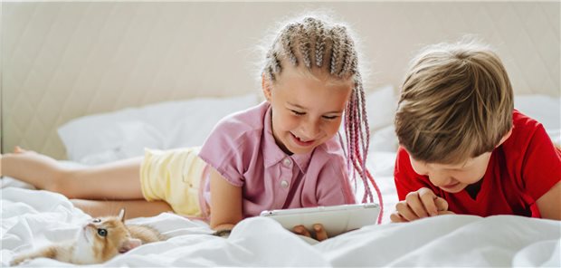 BVKJ-Präsident Fischbach warnt vor zu viel Internet bei jungen Menschen Siblings watching tablet PC lying by ginger kitten on bed
