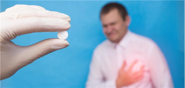 Mann hält sich an die Brust. Davor: eine Hand mit Tablette.