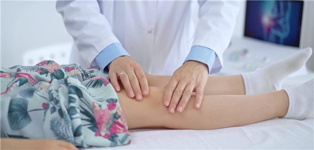 Ein Arzt untersucht das Knie eines Mädchens. 