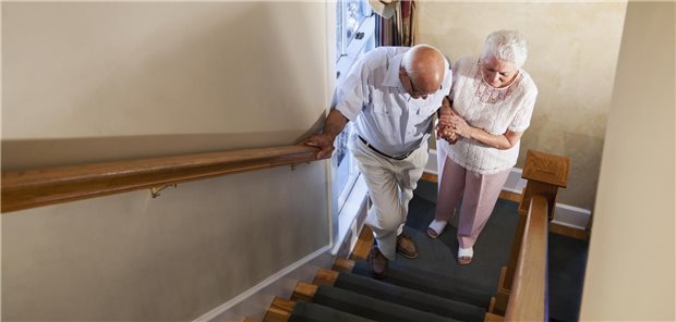 Eine Seniorin hilft ihrem Mann beim Treppesteigen.