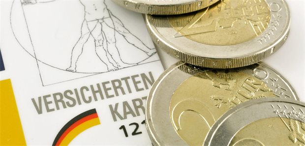 Das Foto zeigt eine Versichertenkarte und Zwei-Euro-Münzen.