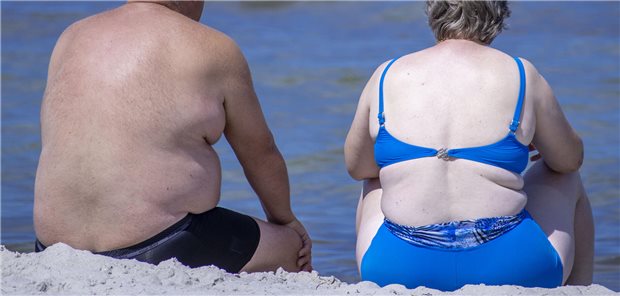 Zwei übergewichtige Personen sitzen am Strand. 