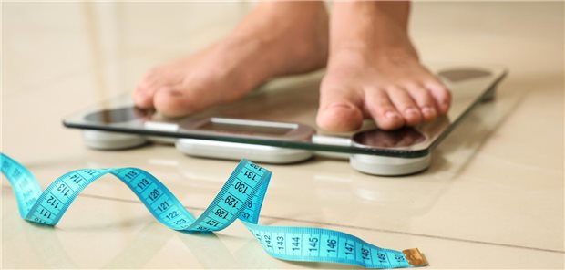 Mensch auf Waage und Maßband.