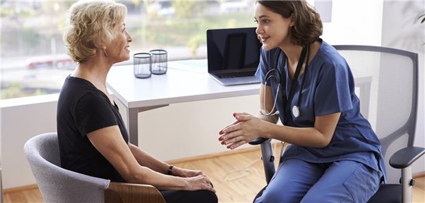 Eine Ärztin sitzt einer Patientin gegenüber und hört ihr zu. 