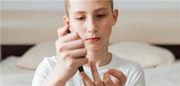 Ein Junge entnimmt sich eine Blutprobe am Finger.