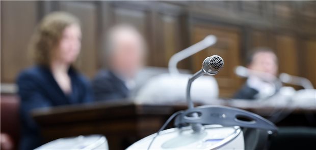 Falsche Masken-Atteste: Arzt zu Bewährungsstrafe verurteilt Der angeklagte Arzt sitzt zwischen seinen Anwälten und Prozessbeteiligten im Gerichtssaal im Strafjustizgebäude.