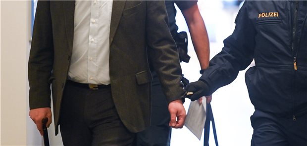Falscher Impfarzt räumt zum Prozessauftakt Vorwürfe ein Der Angeklagte (vorne, l) wird kurz vor Prozessauftakt von Polizisten in das Landgericht Traunstein gebracht. Er soll sich als Arzt ausgegeben und hunderte Patienten gegen Corona geimpft haben