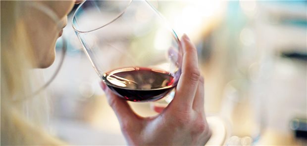 Eine junge Frau hält ein Glas mit Rotwein in der Hand.