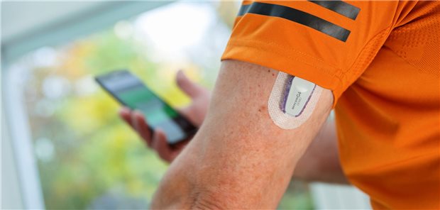 Mann mit CGM-Sensor schaut auf Smartphone