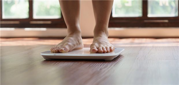 Frau steht auf der Waage. Man sieht nur ihre Füße.