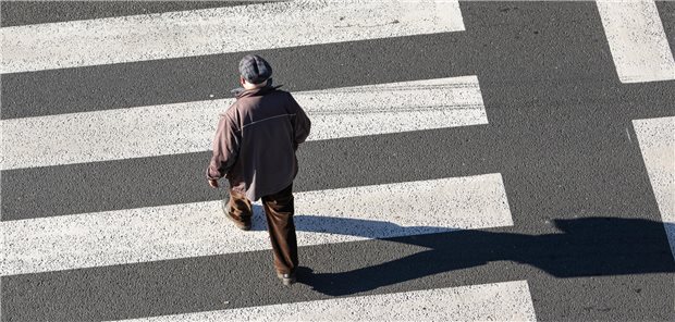 Ein älterer Mann geht über einen Zebrastreifen.