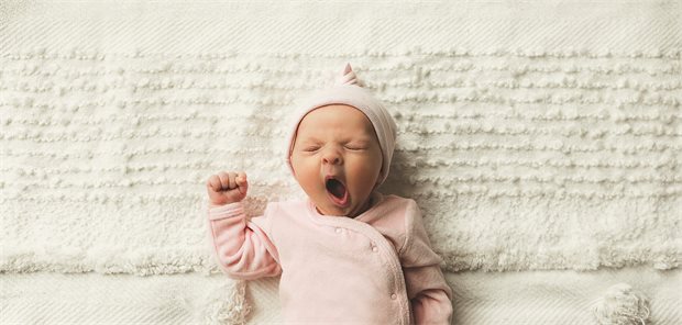 Ein Baby liegt auf dem Boden und spielt.