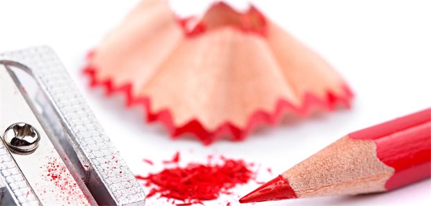 Das Foto zeigt einen gespitzten Rotstift mit Spitzer und Spänen.