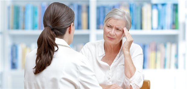 Patientin mit Kopfschmerzen vor Ärztin