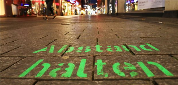 Bund drängt auf schärfere Kontaktbeschränkungen Der Schriftzug „Abstand halten“ steht in der Kölner Innenstadt auf dem Boden. Der Bund will die Kontaktbeschränkungen schon vor Ablauf des Teil-Lockdowns im November drastisch verschärfen.