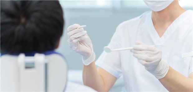 Zahnarzt mit Werkzeug vor einem Patienten.