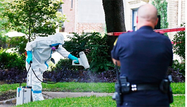 Missstände, Ängste, Hilflosigkeit Der eine arbeitet, der andere schaut zu: Ein Polizist begutachtet in Dallas, wie das Anwesen des Ebola-Infizierten gesäubert wird.