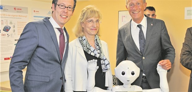 Pflege-Assistenzsysteme – Spagat zwischen Fortschritten und Rückschlägen Der humanoide Roboter Pepper mit Professor Frank Dievernich (l.), Präsident der Frankfurt University of Applied Sciences, Robotikexpertin Professor Barbara Klein und Hessens Staatsminister Axel Wintermeyer.