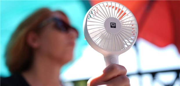 Eine Frau hat einen kleinen Ventilator in der Hand.