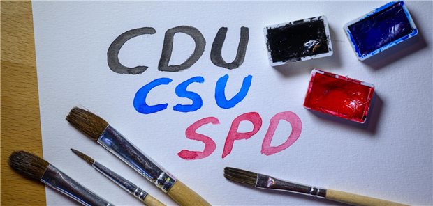 Pinsel und Farbe auf einem Papier, auf dem CDU, CSU und SPD in den jeweiligen Parteifarben steht.