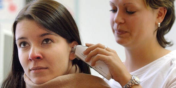 Die Arzthelferin misst bei einer Patientin Fieber.