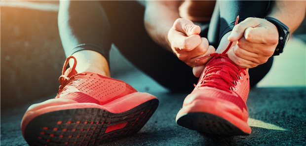 Ein Mann bindet seine Sportschuhe für eine aerobe Trainingseinheit.