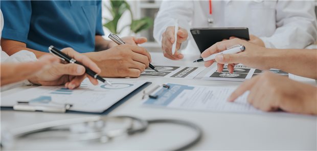 Medizinische Analysten und Ärzte, die in einem Konferenzraum eines Krankenhauses Unterlagen zur Abschätzung des Zehn-Jahres-Risiko für Diabetes einsehen und besprechen.