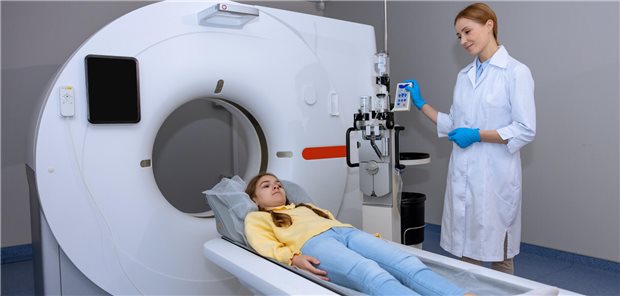 Ärztin mit einem Mädchen, das zur CT vorbereitet wird.
