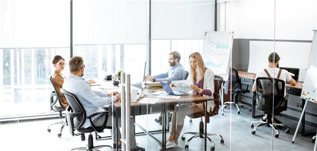 Gruppe von Kollegen, die in einem modernen Büro oder Co-Working-Space an Computern arbeiten.