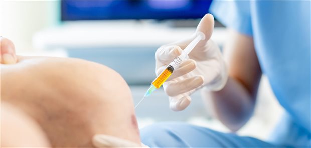 Arzt injiziert eine intraartikulär injizierbarer Substanz (Hyaluronsäure,..) ins Knie eines Patienten mit Arthrose.