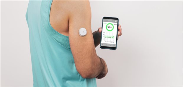Junger Mann zeigt sein Handy auf dem die Daten seiner kontinuierlichen Glukose-Messung angezeigt und überwacht werden.