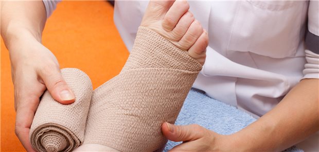 Ärztin bandagiert den rechten Fuß einer Patientin zur Prävention der Entwicklung eines Druckgeschwürs.