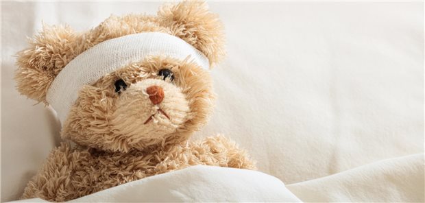 Ein Teddybär mit einem Verband um den Kopf, der im Krankenhaus liegt.