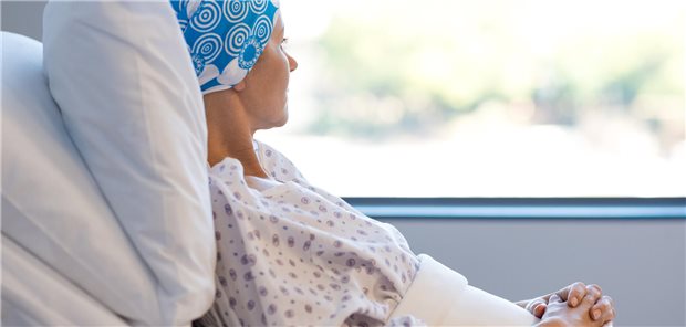 Eine Frau liegt im Krankenbett und schaut aus dem Fenster.