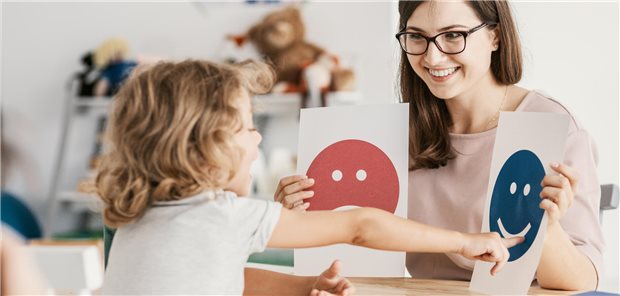 Frau mit Smileys, wobei ein Kind auf den fröhlich schauenden zeigt.