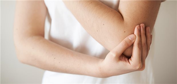 Diese sechs Kriterien sprechen gegen einen „Tennisarm“ Eine junge Frau fasst sich an ihren schmerzenden Ellenbogen.