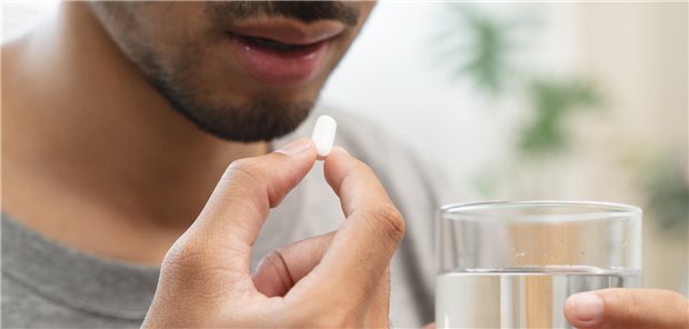 Mann mit Tablette und einem Glas Wasser