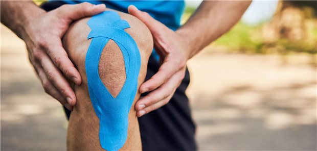 Nahaufnahme eines männlichen Läufers, der an seinem rechten Knie mit Kinesiologie-Tape trägt.